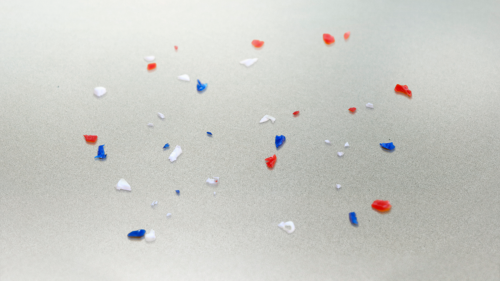 Close-up of colorful microplastic particles on the surface of an aluminum-coated membrane
