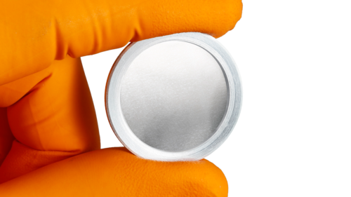 A hand with orange glove holding a aluminum-coated membrane assembled in an aluminum ring